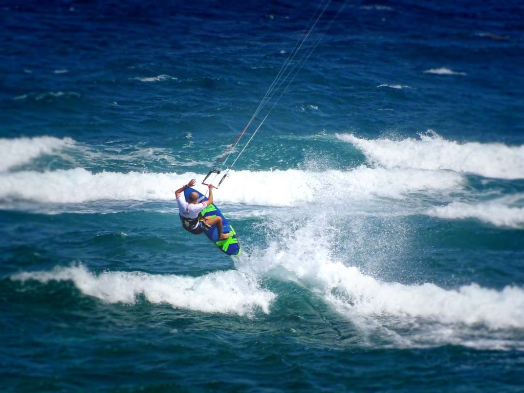 Homme en surfkite effectue saut de vague en Guadeloupe